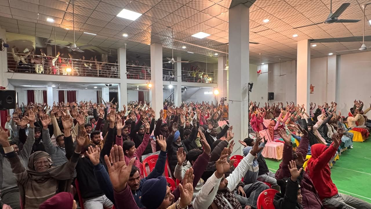 Indoor gospel meeting with congregation hands raised