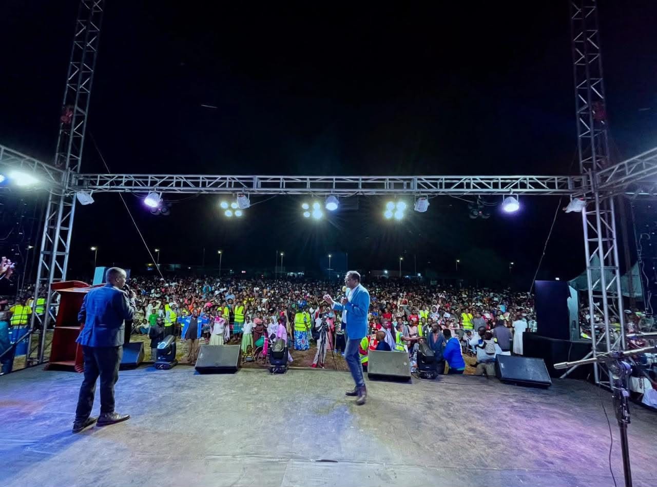 Outdoor crusade stage with crowd at night